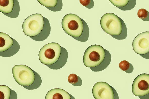 Avocado on green background pattern top view flat lay stock photo