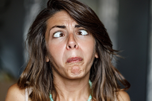 disgusted and frowning young woman on white background