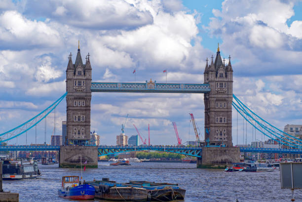 Famous Tower Bridge with Thames River in the foreground at City of London on a blue cloudy summer day. Photo taken August 1st, 2022, London, England.