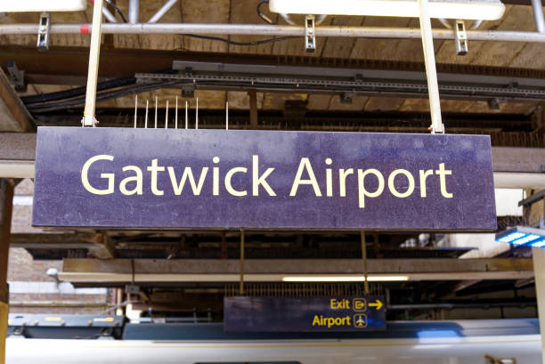 Public transport station at English airport. Sign at Railway station with platform and leaving white train of Thames Link at Gatwick Airport London on a cloudy summer day. Photo taken July 1st, 2022, Gatwick, United Kingdom. gatwick airport photos stock pictures, royalty-free photos & images