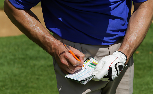 A golfer keeping score on the scorecard.