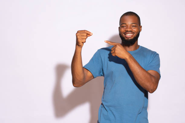 istock Black man with a blue t-shirt smiling and holding a copy space with hands on a white background. 1436704754