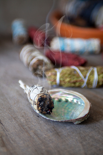 A vertical shot of a bundle of dried sage herb, performing smudging ritual, cleansing negative energy, and purifying living space with smoke