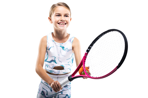 Young female tennis player. Little girl posing with racket and ball isolated on white background.