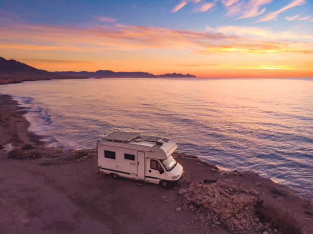 Aerial view. Camper car rv camping on coast sea shore at sunrise. Adventure, travel with mobile home.