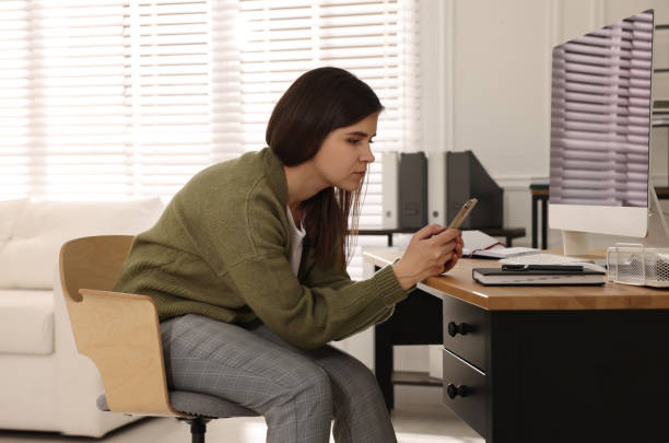 istock Young woman with bad posture using smartphone in office 1436710782