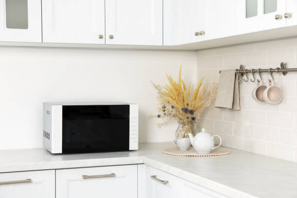 istock Modern microwave oven, dry flowers, cup and teapot on countertop in kitchen 1436712213