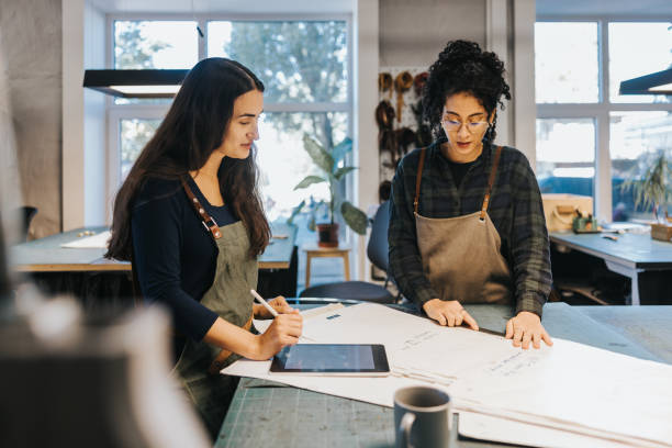 istock Two Latin woman working with blueprint in their leather studio 1436712459