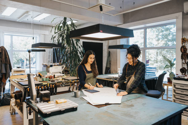 istock Two Latin woman working with blueprint in their leather studio 1436712485