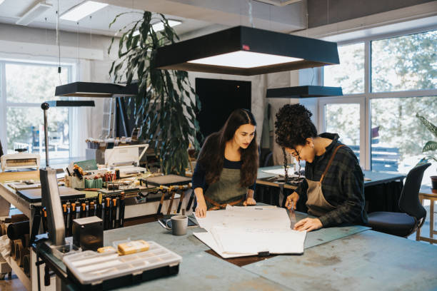 istock Two Latin woman working with blueprint in their leather studio 1436712497