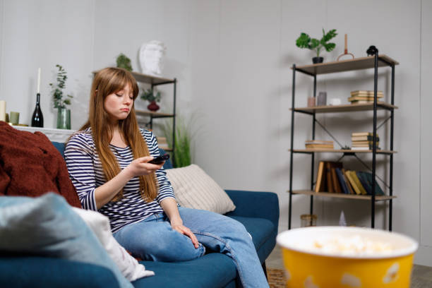 istock Sad girl with TV remote control on sofa 1436712673