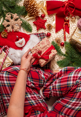 Woman sitting with Christmas presents on Christmas day in Pyjamas