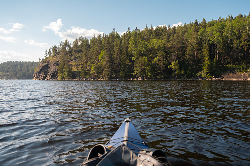 Ladoga lake. Panorama of the Republic of Karelia. Northern nature of Russia. View from the blue kayak from the water. Boots on the bow of the boat.