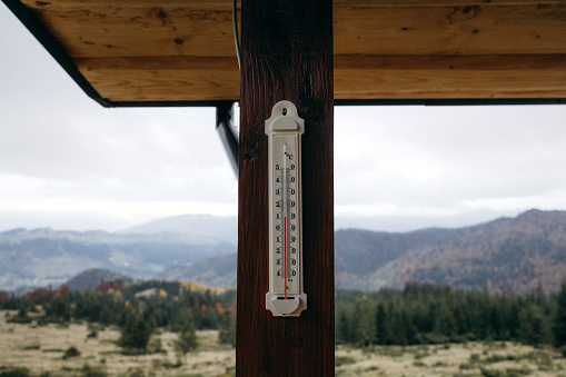 The thermometer on the pillar of the house outside in the mountains in autumn