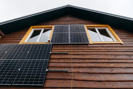 The solar panels attached to the wall of a wooden house