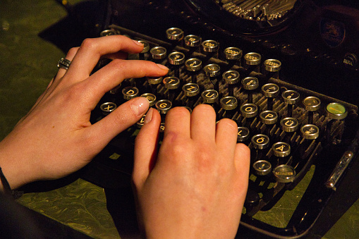 Two human hands writing on old typing machine