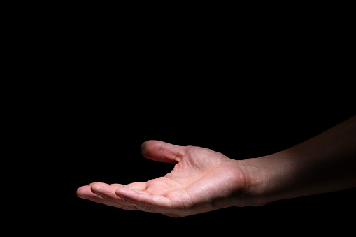 Parts of a male hand outstretched on a black background