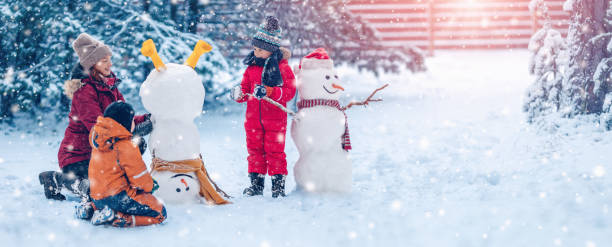 Family building a cute snowman in the snowy park. stock photo