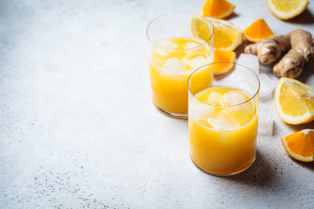 Orange lemon juice with ginger and spices in glass, gray background. Immunity boosting drink, health concept, recipe for colds. stock photo