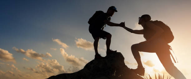 istock hikers team climbing up mountain cliff at sunset. giving helping hand. teamwork and assistance concept. banner with copy space 1436719791