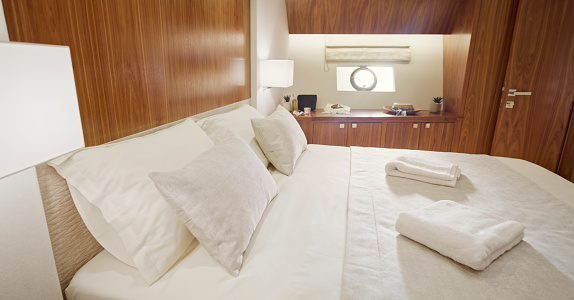 Empty bed in luxurious yacht cabin.