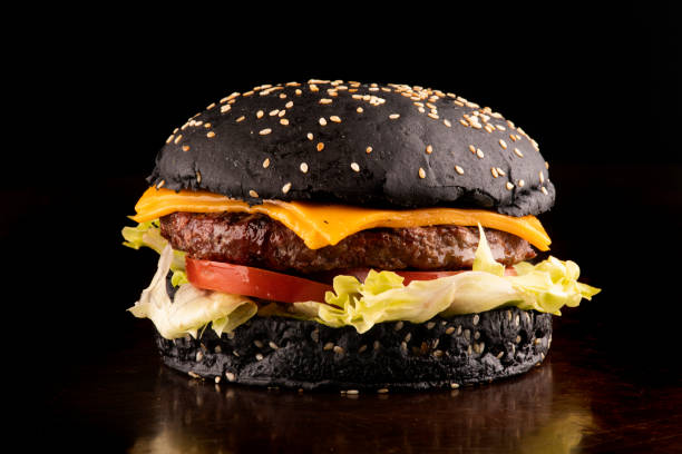ジューシーなハロウィーンをテーマにしたハンバーガートマト、キャットテールにゴマを添えたブラックバーンレタスを正面からクローズアップ - hamburger bun bread isolated ストックフォトと画像
