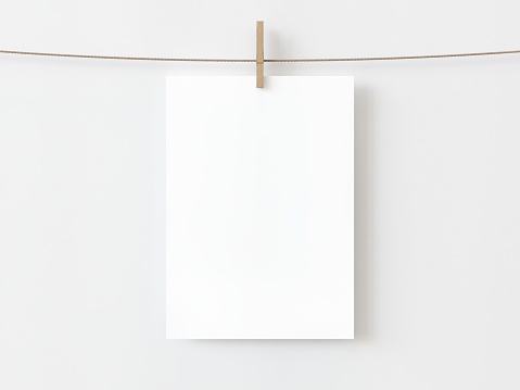 One blank vertical rectangle note paper card hanging with wooden clip or clothespin on rope string peg isolated on white backgroun. 3D illustration