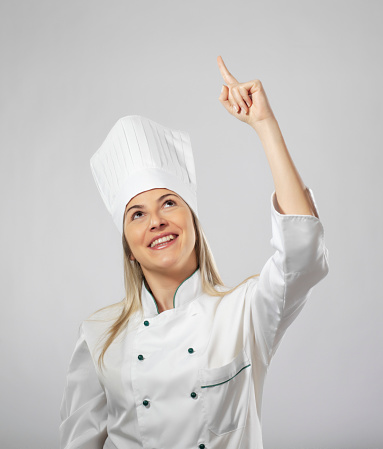 Female chef portrait pointing up on white background