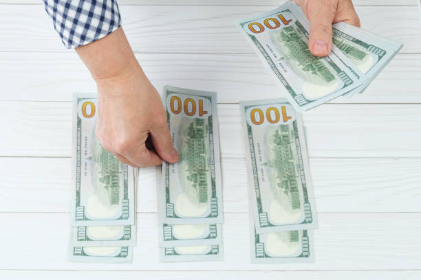 istock Two hands of a woman with a stack of one hundred dollar bills 1436726949