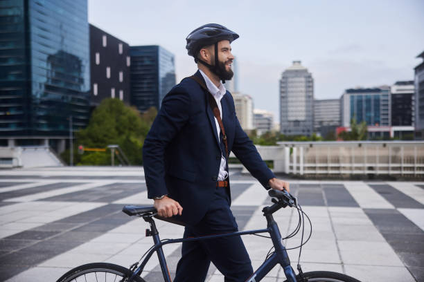 istock Young businessman smiling while walking with his bike after work 1436730640