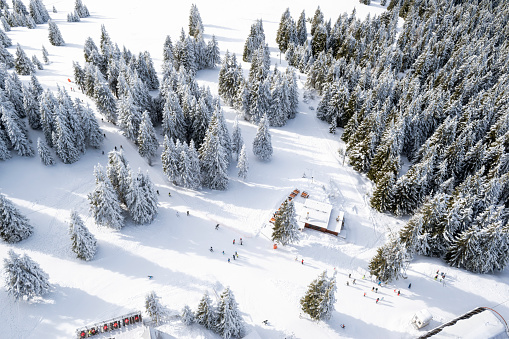 Winter wonderland in ski resort Pamporovo, Bulgaria. Aerial view of snow capped mountains, unrecognizable tourists skiing on slopes. Christmas holiday, winter vacation, travel destination