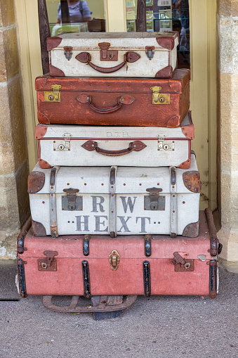 Cranmore, Somerset, England - 01 September, 2022: Part of a nostalgic display of railroad paraphernalia, this stack of old-fashioned luggage loaded onto a sack barrow is situated on the station platform at Cranmore on the East Somerset Railway in Somerset, England.