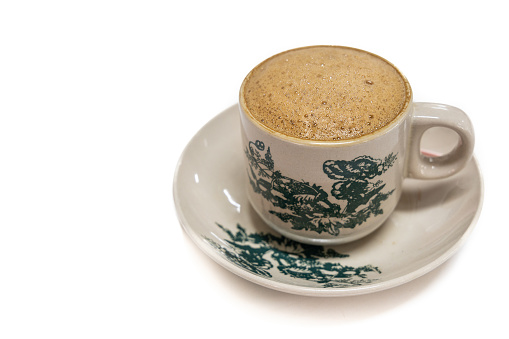 Traditional aromatic coffee served in vintage kopitiam cup and saucer in white background at coffee shop