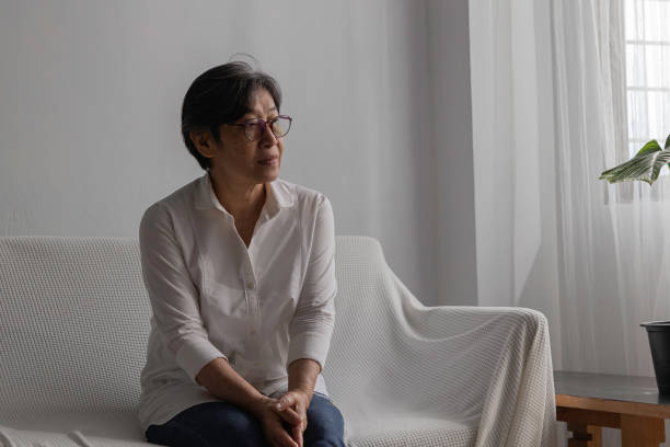 istock late age woman sit lonely on white sofa look out window, feel alone. 1436731683