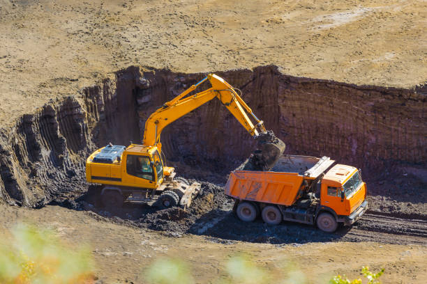 escavadeira carregando um caminhão de lixo em uma pedreira - caterpillar truck - fotografias e filmes do acervo