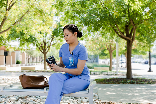 The nurse sits outside to take a break and read an article on her phone.