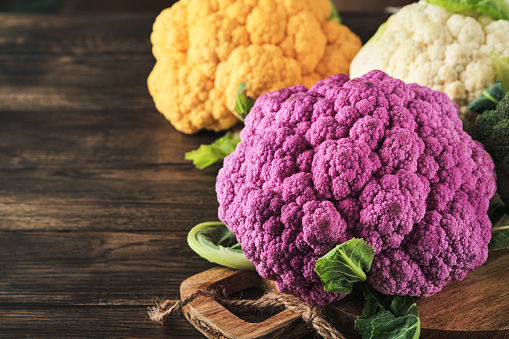 Colorfu cauliflower. Various sort of cauliflower on old wooden background. Purple, yellow, white and green color cabbages. Broccoli and Romanesco. Agricultural harvest. Mock up.