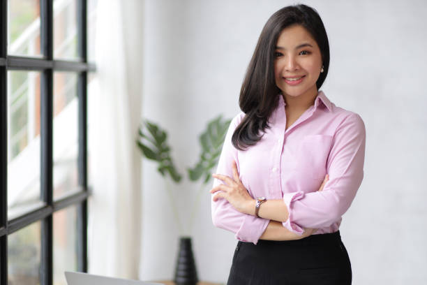 Portrait of a charming young Asian businesswoman in the office standing and looking at the camera. stock photo