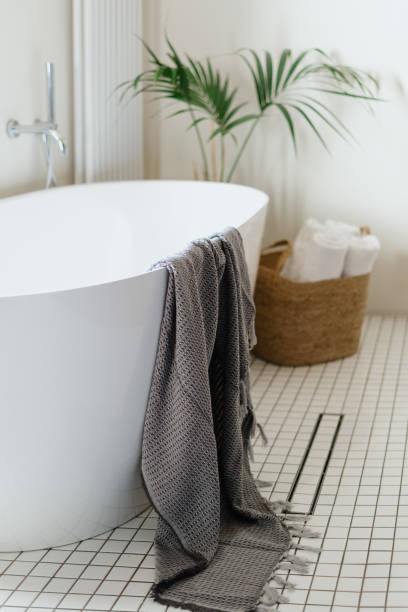 istock Bathroom interior with bathtub, towels and water drain on tiled floor 1436740948