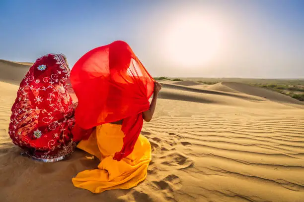 Photo of Two Indian girls watching a sunset on a sand dune, desert village, India