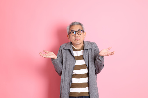 The 40s adult Asian man stnading on the pink background with casual clothes.
