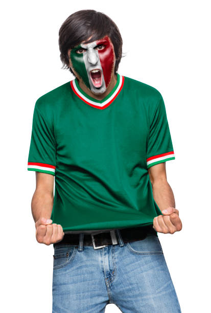 Soccer fan man with jersey and face painted with the flag of the Mexico team screaming with emotion on white background.