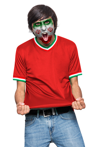 Soccer fan man with jersey and face painted with the flag of the IR IRAN team screaming with emotion on white background.