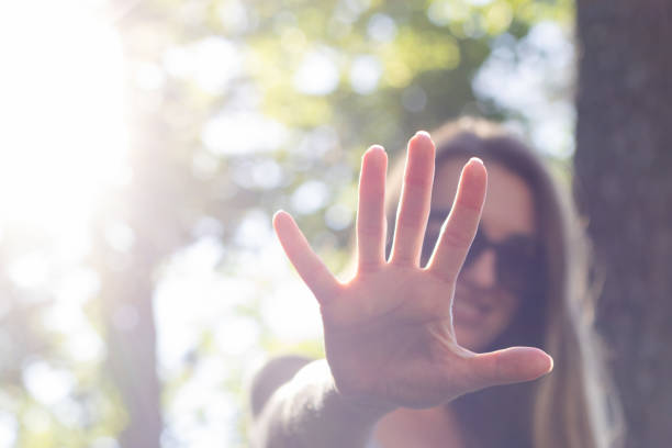 istock Smiling woman showing her palm or 5 fingers gesture. Selective focus, blurred. 1436747577