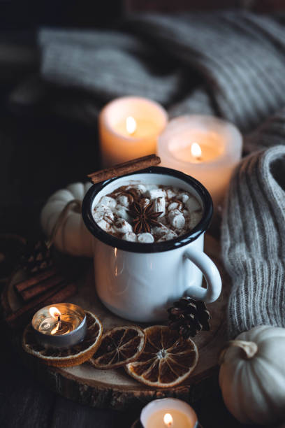 istock Autumn cozy home composition with hot chocolate with marshmallow and candles. Aromatherapy on a grey fall morning, atmosphere of cosiness and relax. Wooden background, window sill, close up. 1436757099