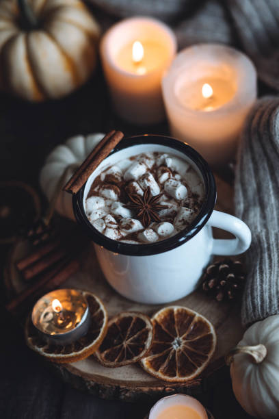 istock Autumn cozy home composition with hot chocolate with marshmallow and candles. Aromatherapy on a grey fall morning, atmosphere of cosiness and relax. Wooden background, window sill, close up. 1436757103