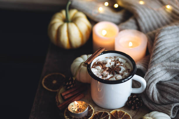 istock Autumn cozy home composition with hot chocolate with marshmallow and candles. Aromatherapy on a grey fall morning, atmosphere of cosiness and relax. Wooden background, window sill, close up. 1436757125