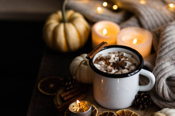 istock Autumn cozy home composition with hot chocolate with marshmallow and candles. Aromatherapy on a grey fall morning, atmosphere of cosiness and relax. Wooden background, window sill, close up. 1436757143
