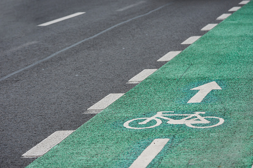 Bicycle road mark on a green lane next to car lane sectioned by a disrupted white line