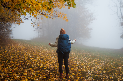 Confused tourist does not know which way to go. Lost hiker in fog. Worried woman with backpack hiking in autumn forest